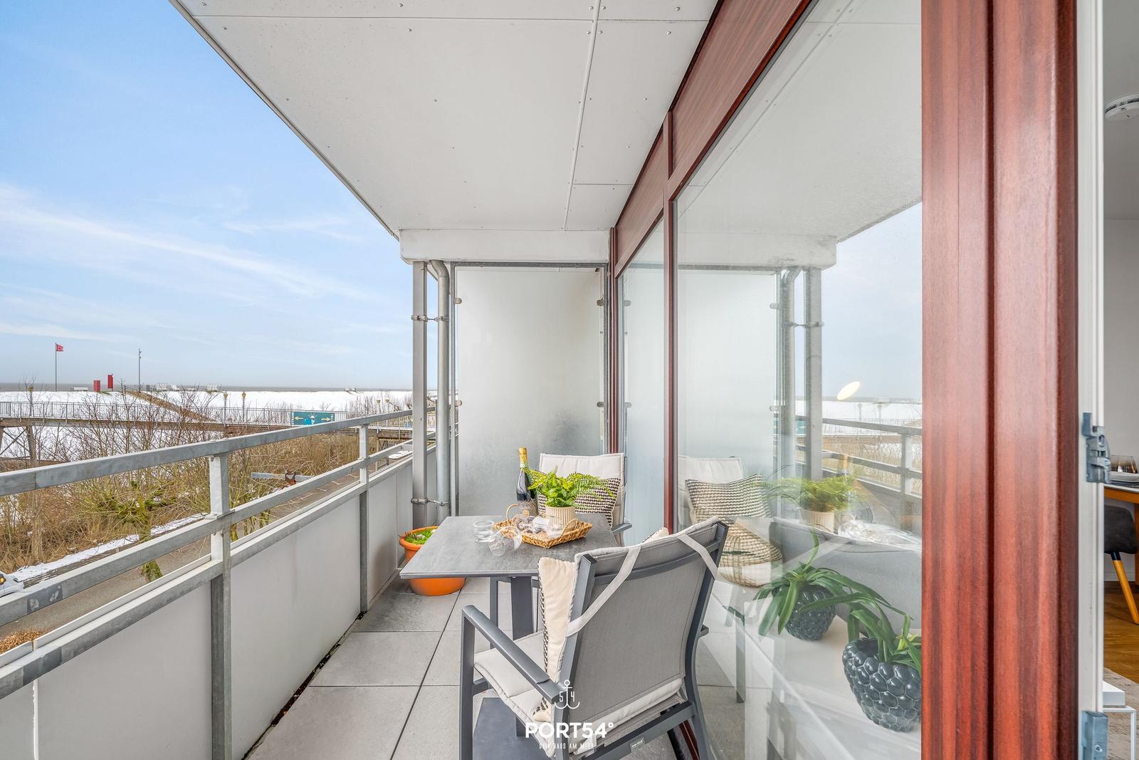 Terrasse mit Tisch, Stühlen und Blick auf Strand und Himmel