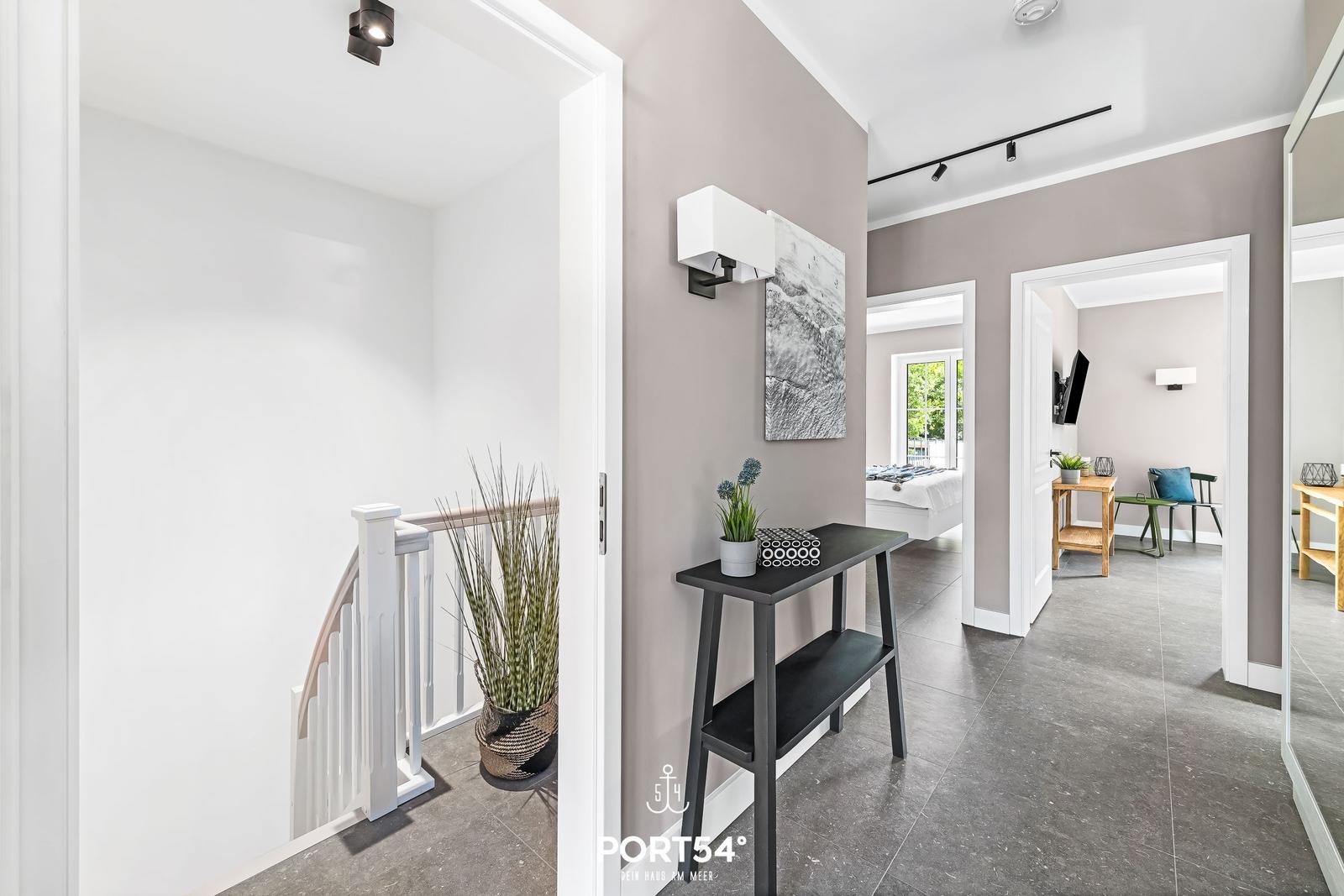 Flur mit Treppe, Schminktisch und Blick in Schlaf- und Wohnzimmer.