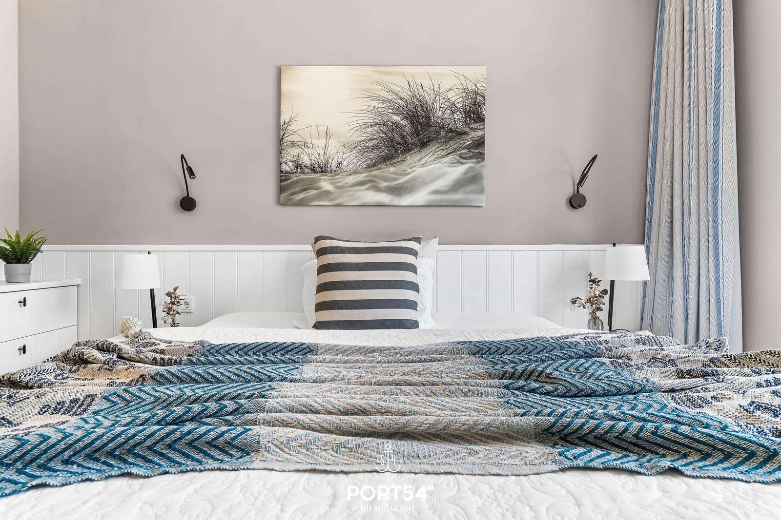 Schlafzimmer mit Bett, Wandbild und Vorhängen.