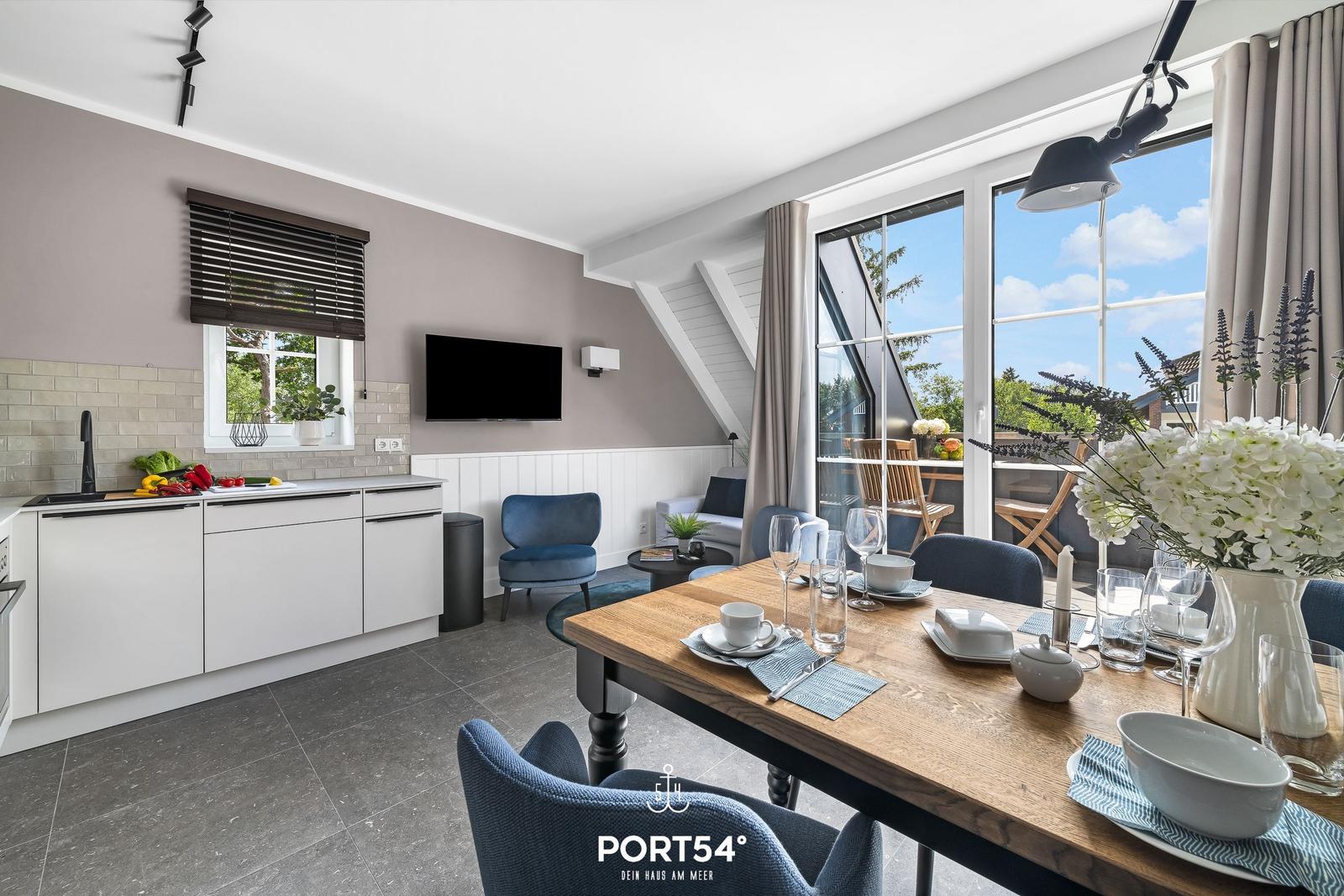 Küche und Esszimmer mit Tisch, Stühlen und Blick auf Balkon.