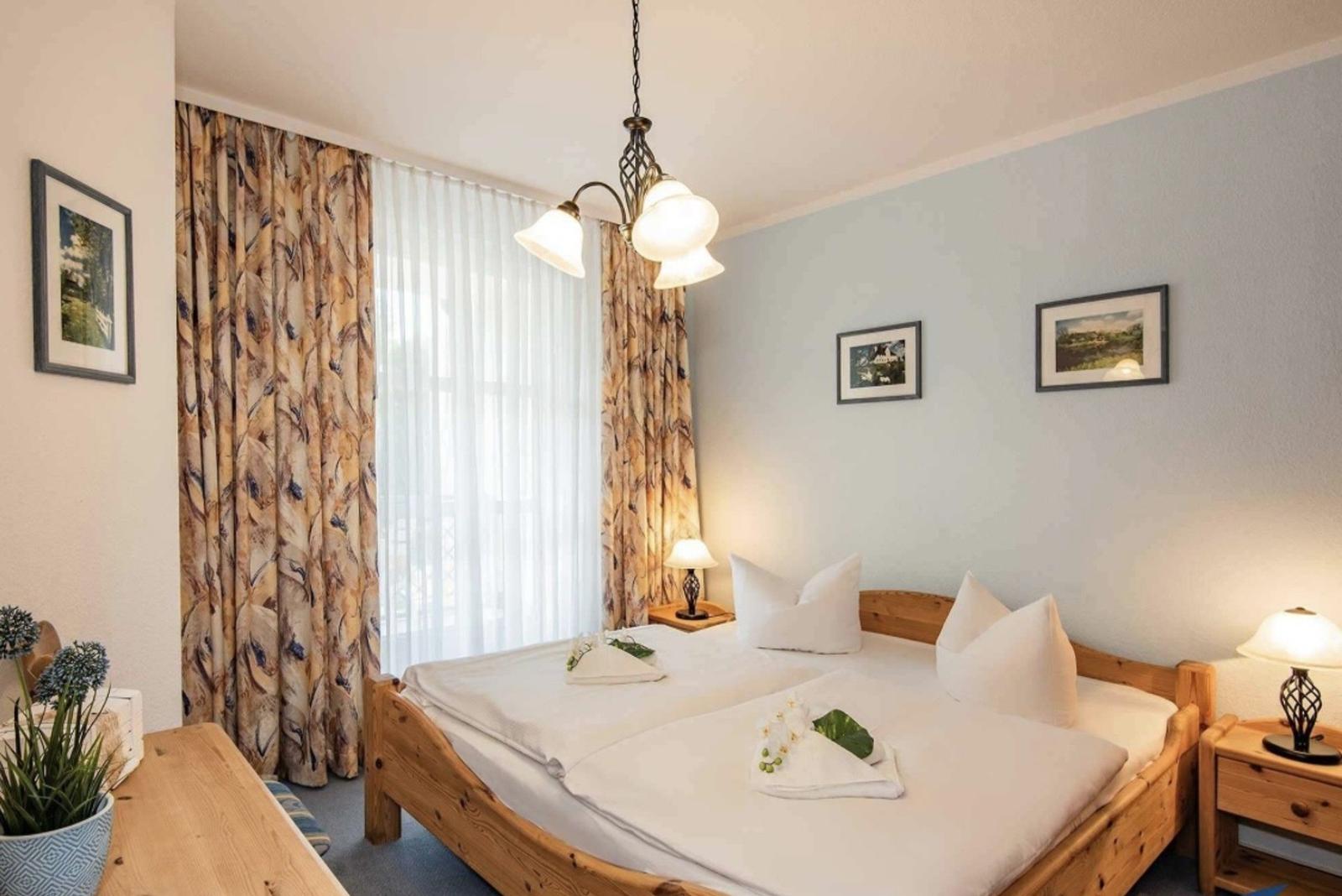 Schlafzimmer mit Holzbett, Fenster und Nachttischen.