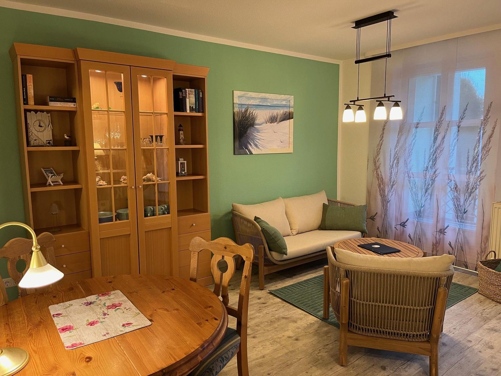 Esszimmer mit Wohnbereich, Holzmöbel und grüner Wand.
