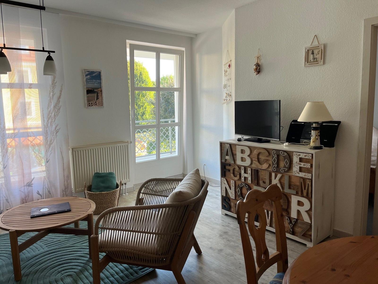 Wohnbereich mit Sitzgelegenheit, TV und Fenster zur Außenterrasse.