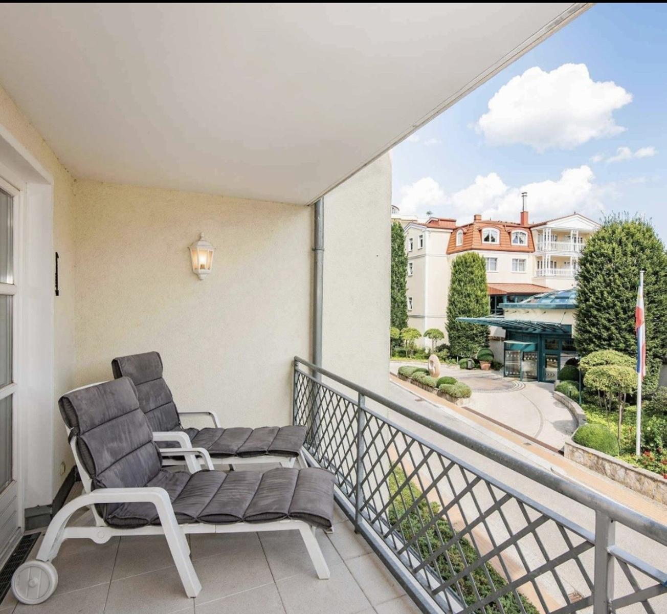 Terrasse mit zwei Liegestühlen und Blick auf Hotelanlage.