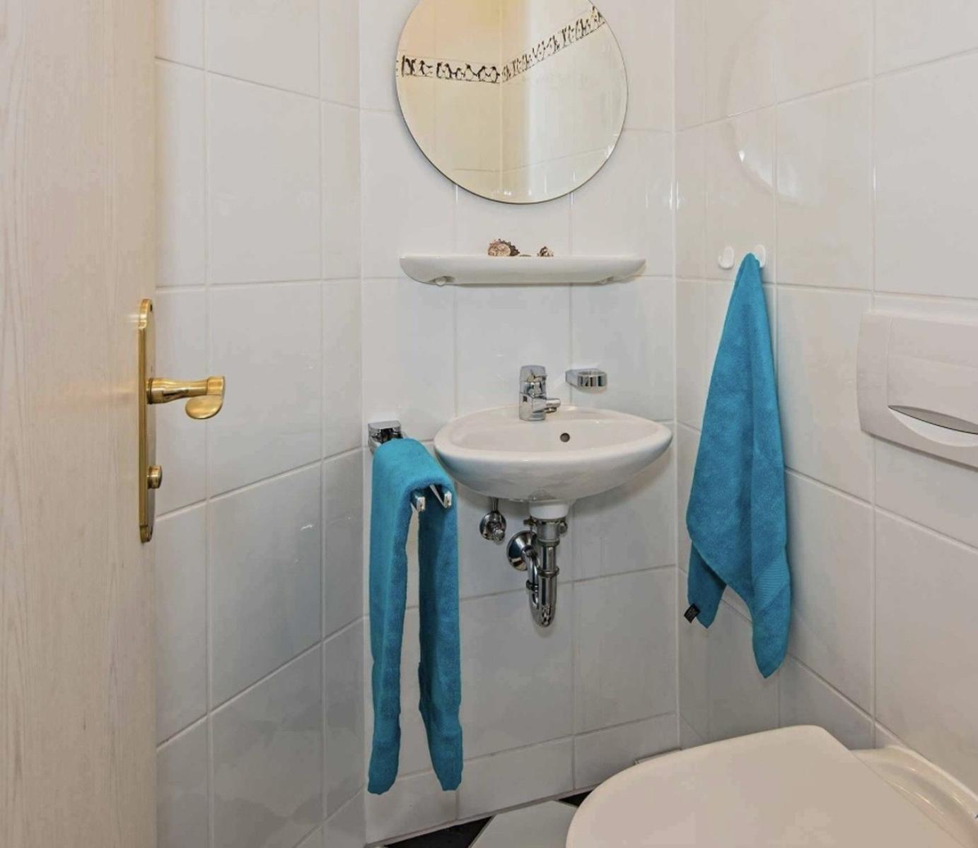 Badezimmer mit Waschbecken, Spiegel und blauen Handtüchern.