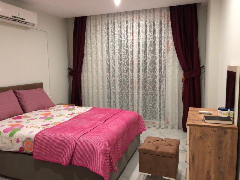 Schlafzimmer mit Bett, Vorhängen und Schreibtisch.