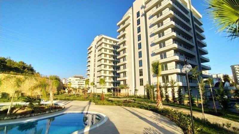 Modernes Apartmenthaus mit Pool und Palmenanlage im Freien.
