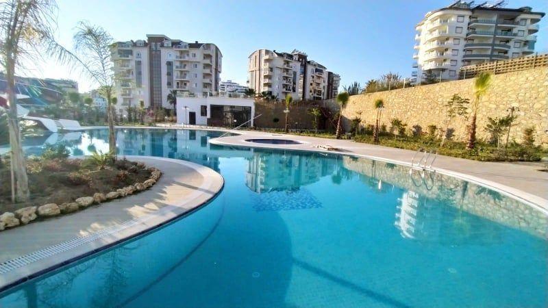 Großer Swimmingpool mit moderner Umgebung und mehreren Hochhäusern im Hintergrund.