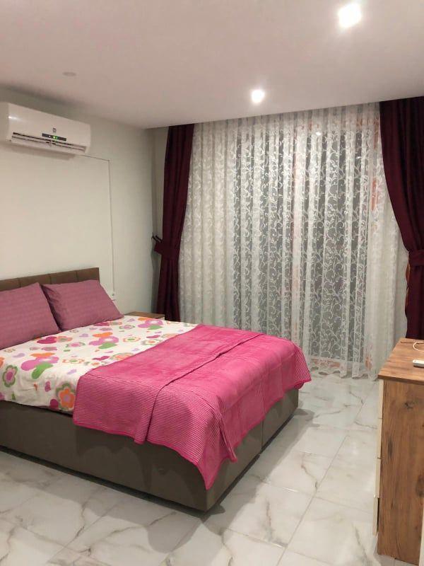 Schlafzimmer mit Bett, Vorhängen und Klimaanlage.