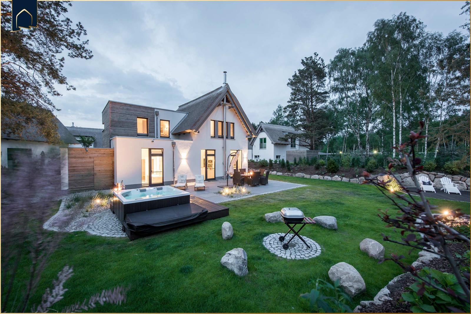 Moderne Villa mit Whirlpool, Grill und Garten. Umgeben von Bäumen und einem gepflegten Rasen.