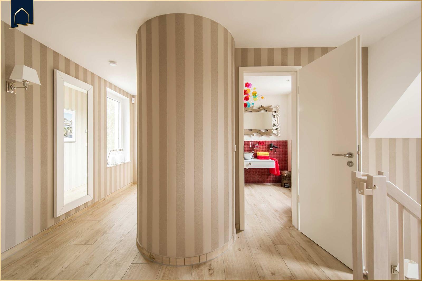 Flur mit gestreifter Wand, Tür zum Bad und Spiegel an der Wand.