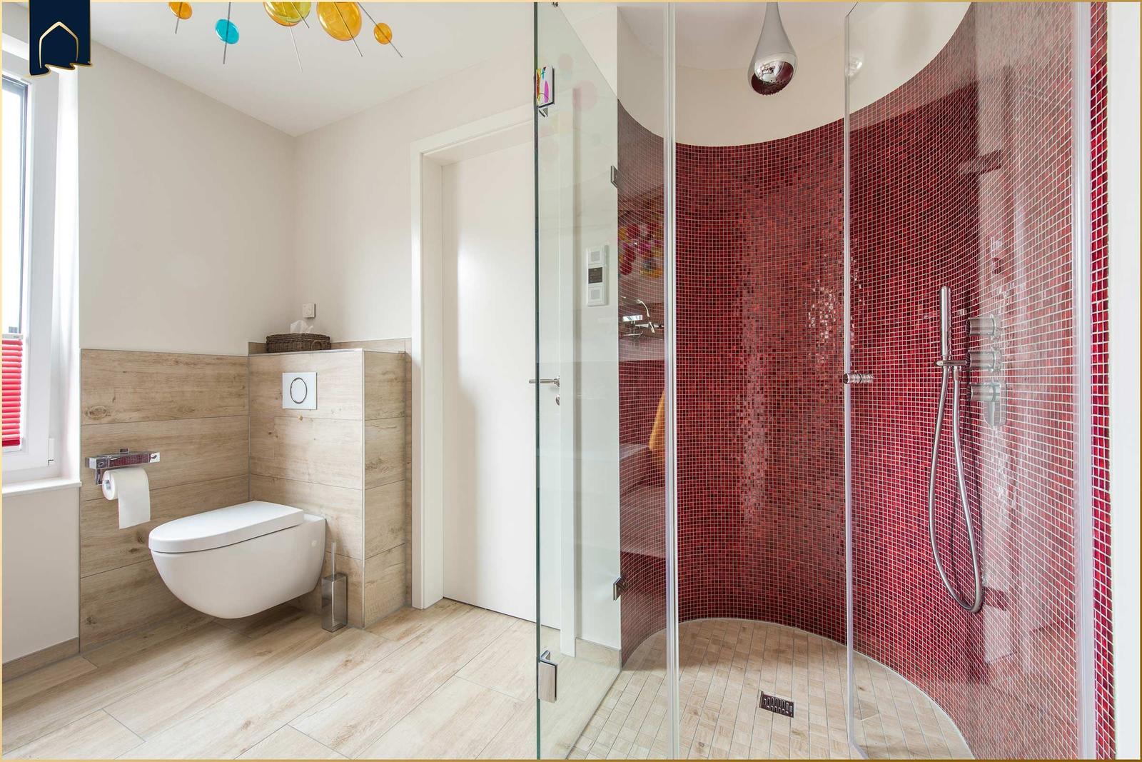Bad mit Dusche und Toilette. Duschbereich mit roten Mosaikfliesen.