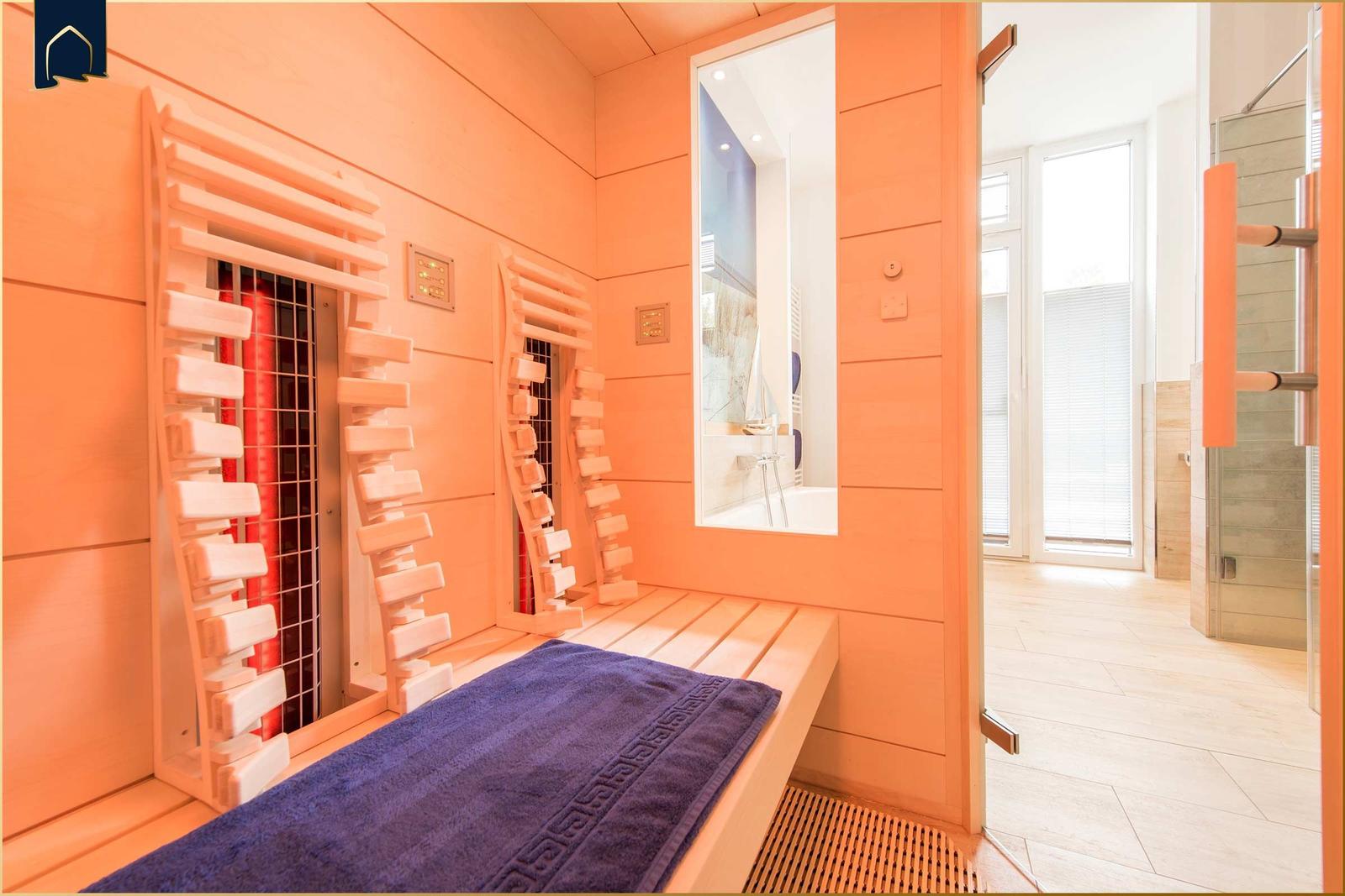 Sauna mit Holzbank, Heizung und Blick in das Bad.