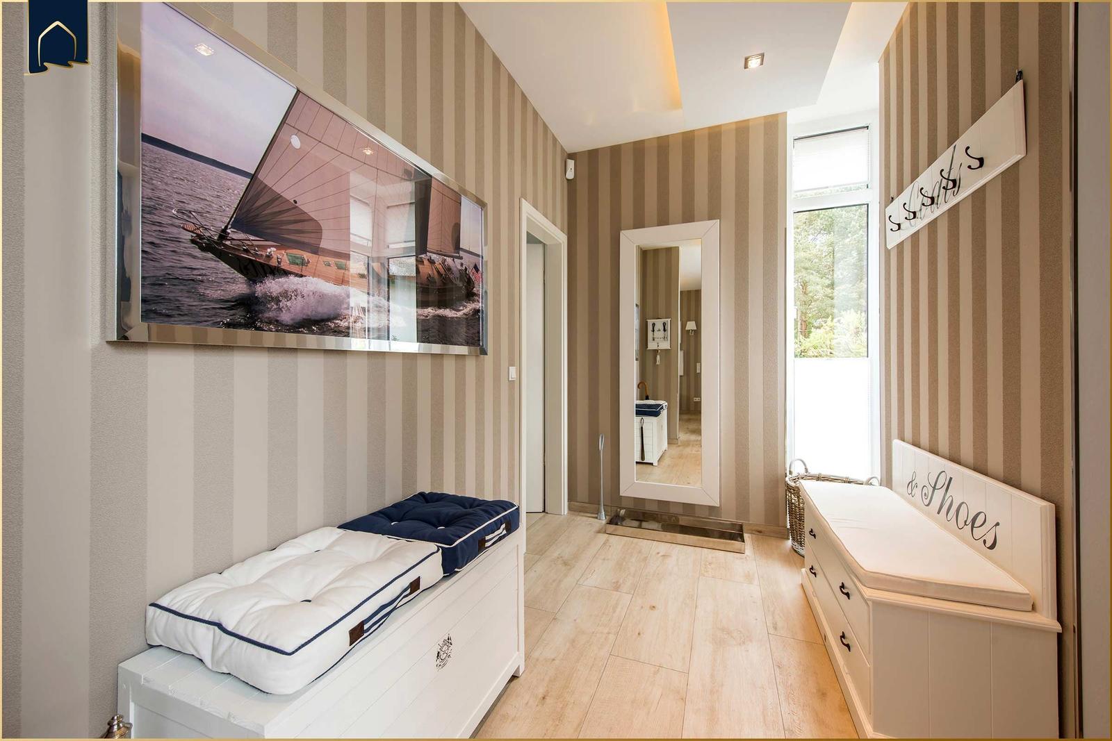 Flur mit gestreifter Tapete, Sitzbank und Wandbild mit Segelboot.