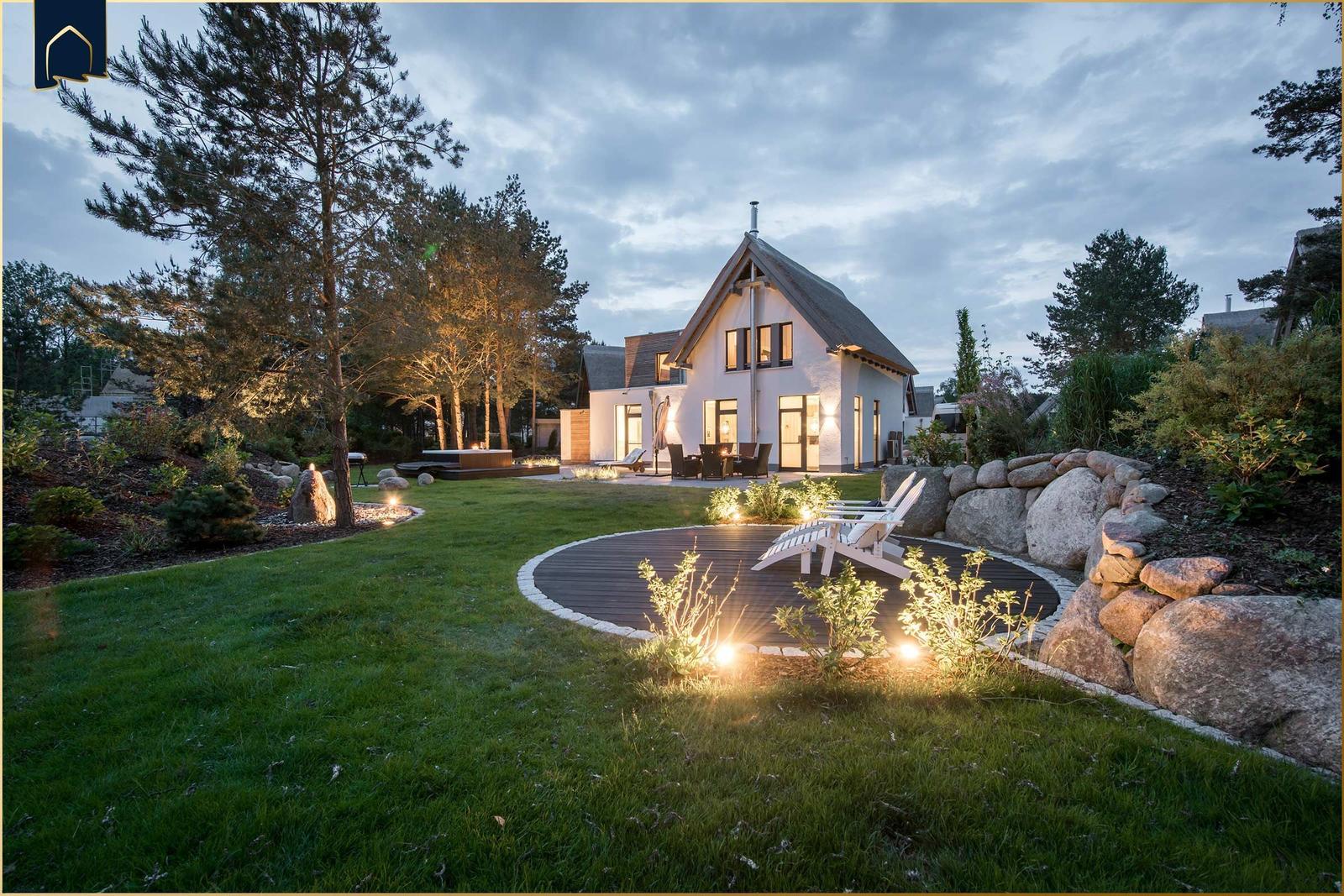 Ein Haus mit großem Garten, Terrasse und Sitzgelegenheiten bei Dämmerung.