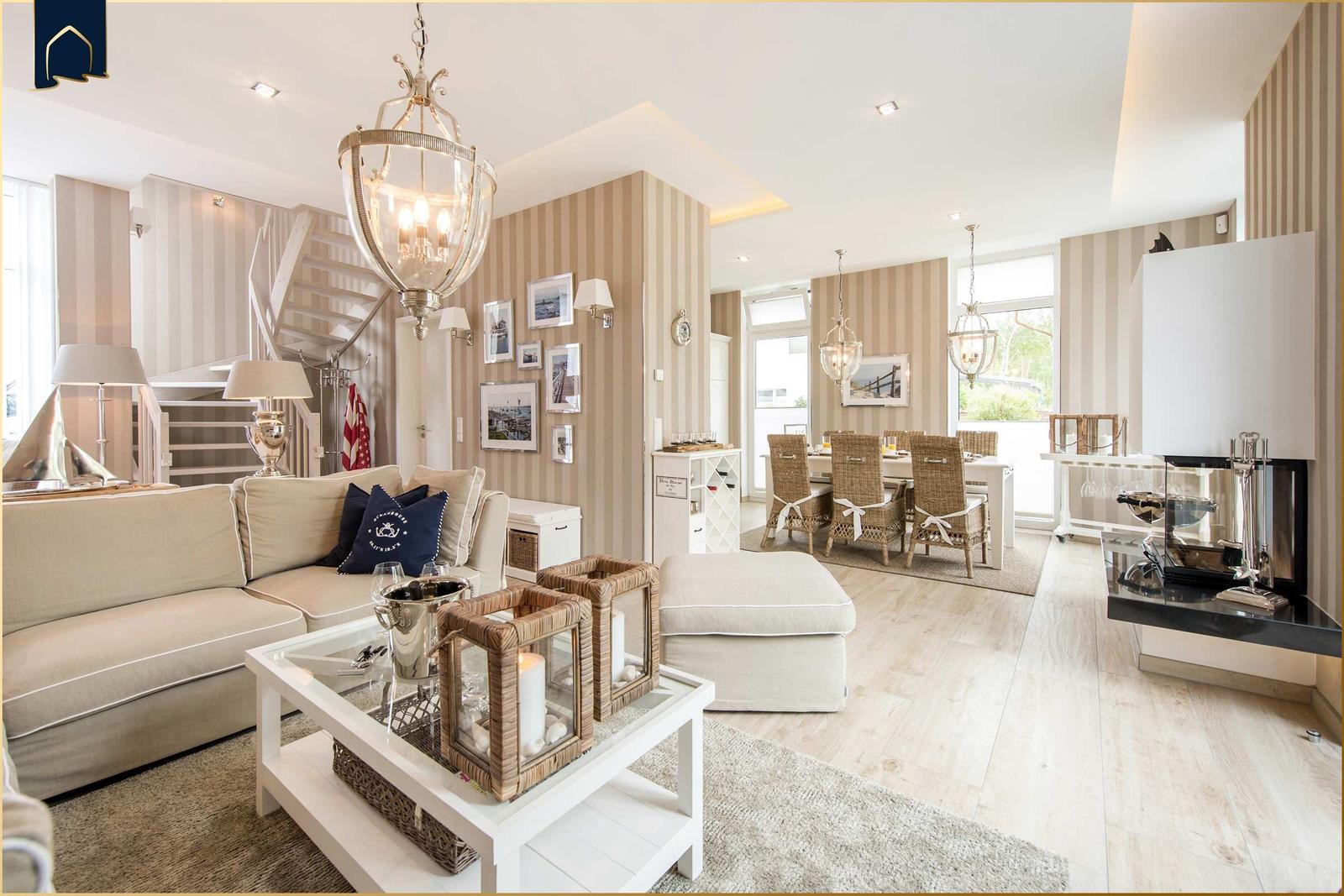 Wohn- und Essbereich mit Sofa, Esstisch und Kamin. Streifenwand und helles Holzfußboden.