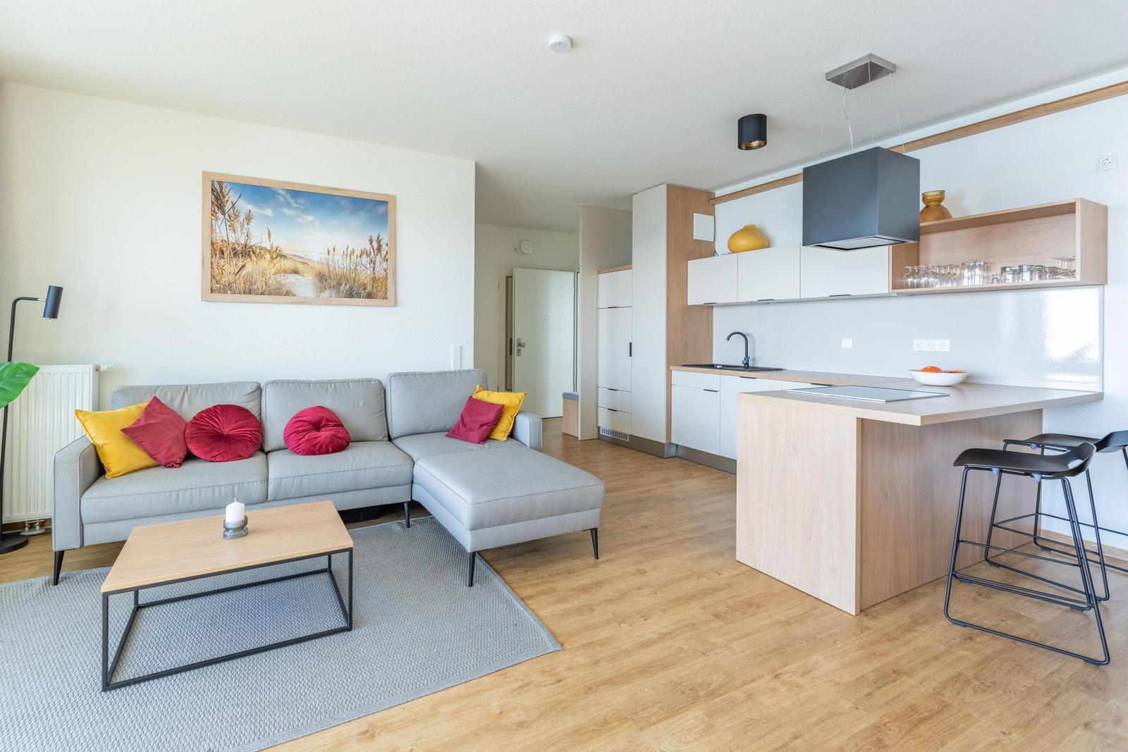 Wohnbereich mit Sofa, Couchtisch und offener Küche mit Kücheninsel.
