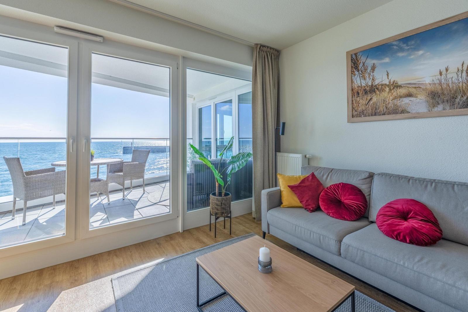 Wohnzimmer mit Sofa, Couchtisch und Balkonblick auf das Meer.