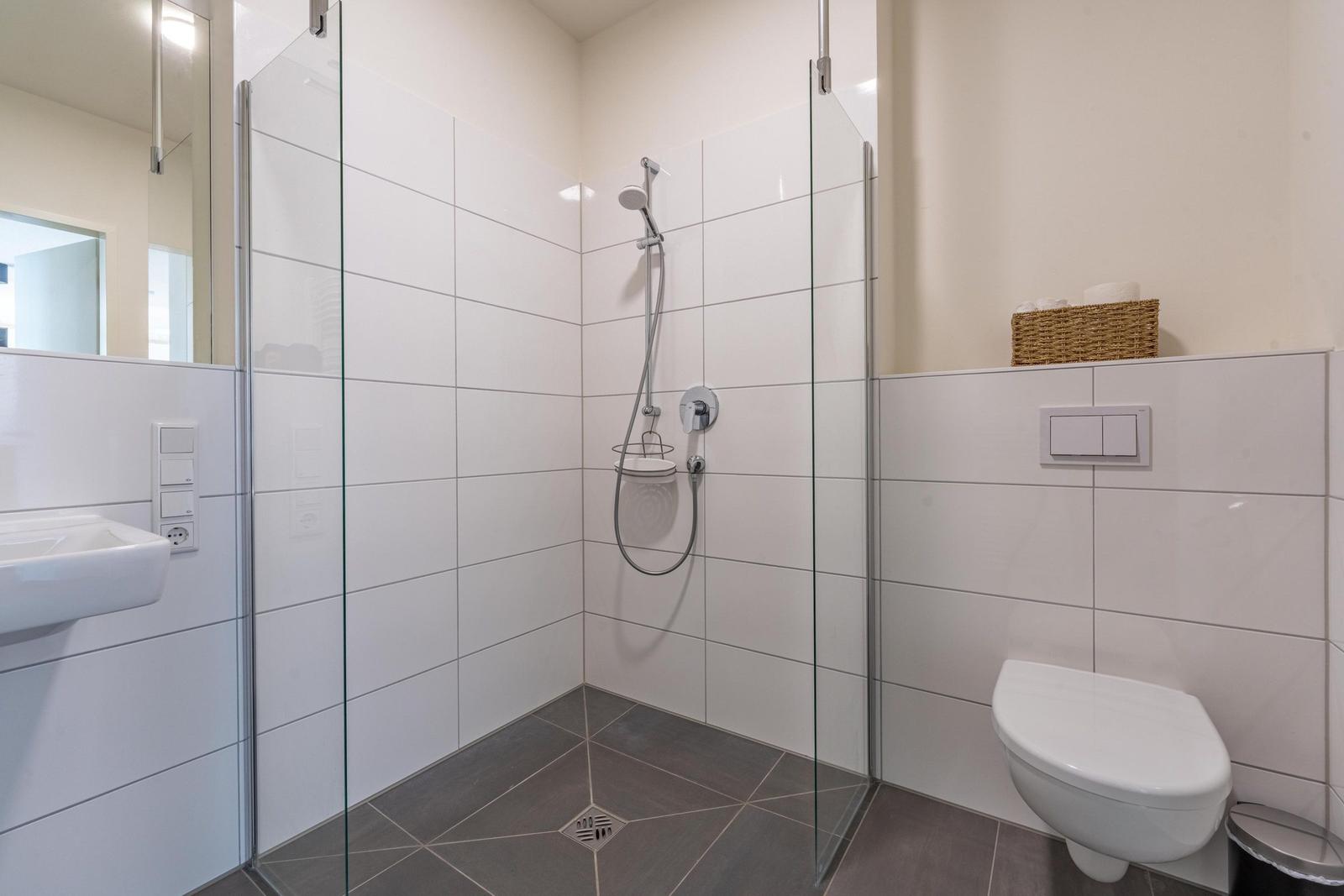 Badezimmer mit Dusche, Toilette und Waschbecken.