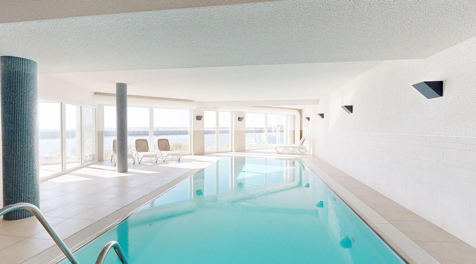 Innenpool mit Blick aufs Meer und Liegen