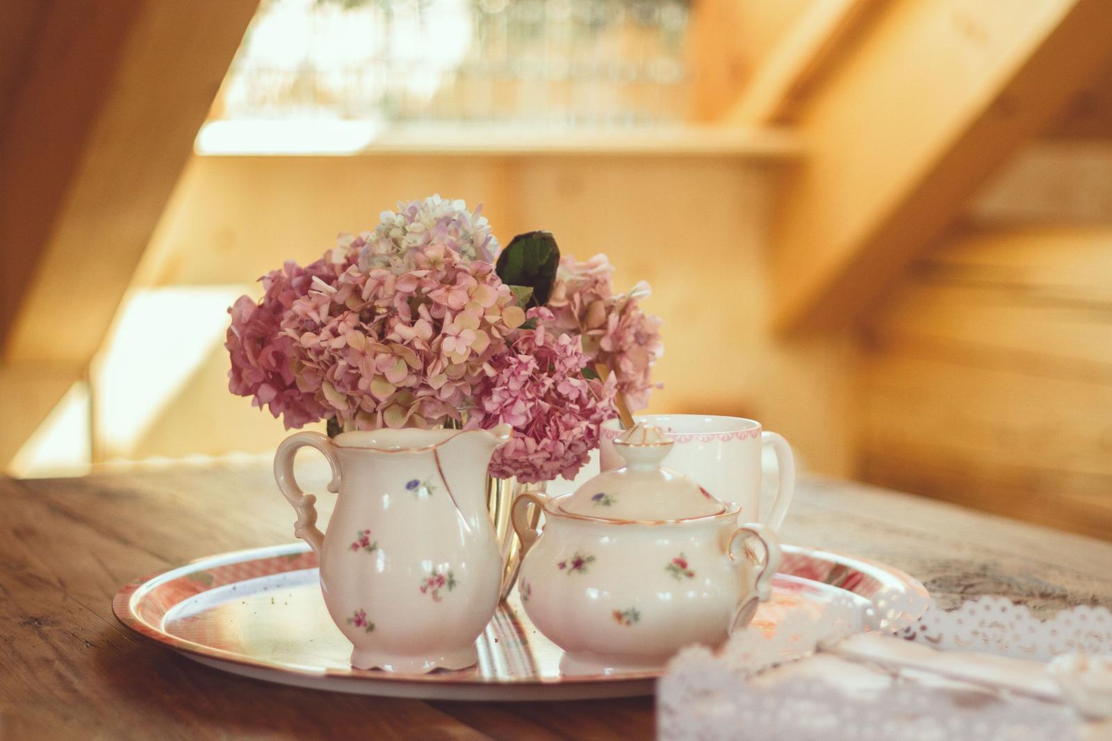 Auf einem Holztisch steht eine Teeservice mit Blumenstrauß.