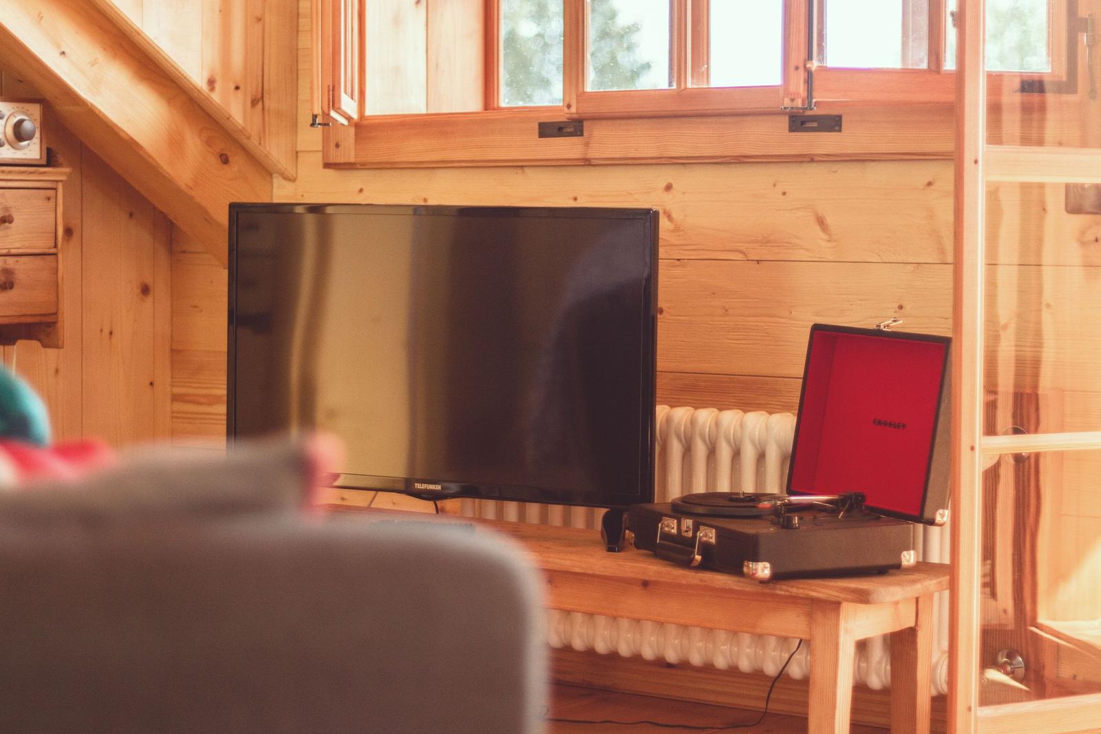 Ein Fernseher und eine Plattenspieler stehen auf einem Holztisch in einem Raum mit Holzwänden.