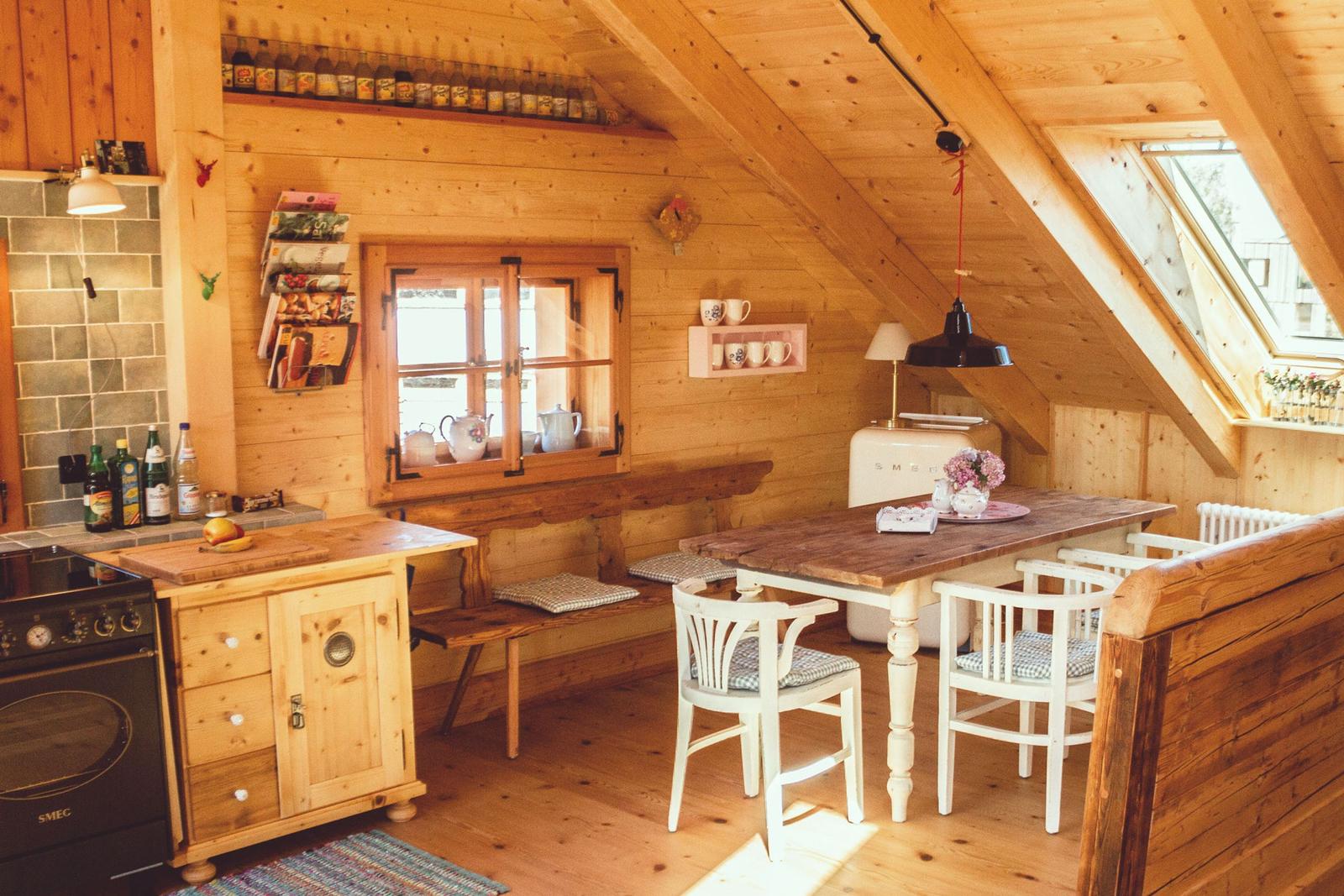 Küche mit Essbereich, Holzwände und -decke, Fenster und Schränke.