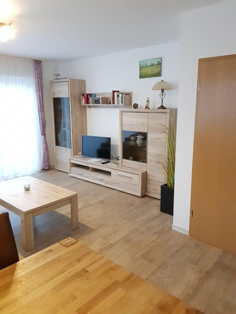 Living room with wooden furniture, TV, and large windows.