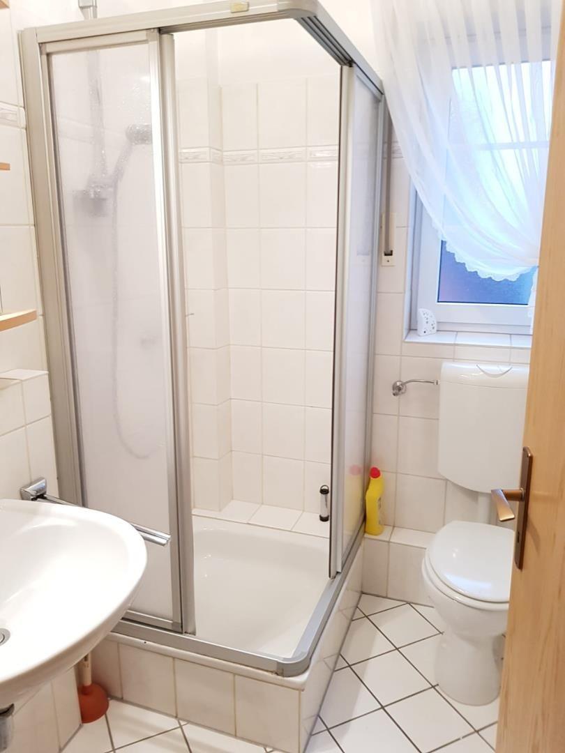 Bathroom with shower, toilet, and sink. Window with curtain.