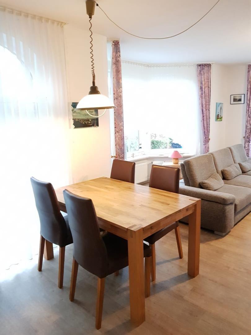 Dining room with wooden table and chairs, living area with sofa and windows
