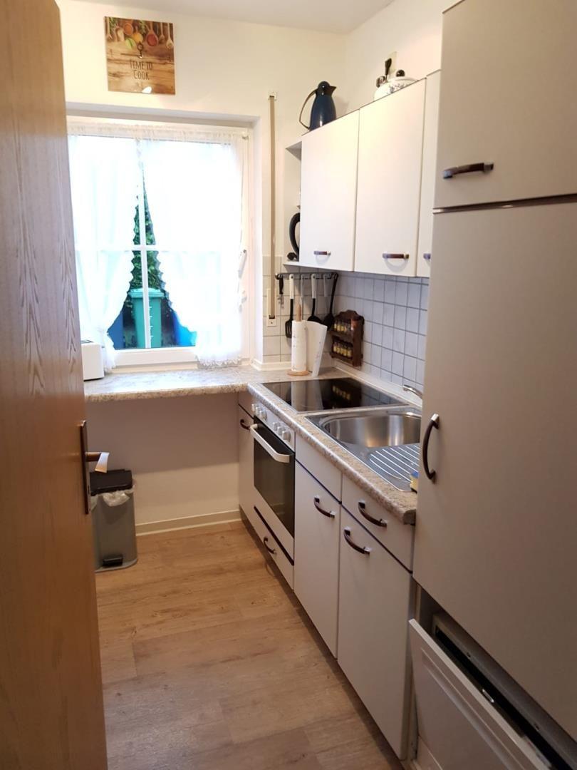 Kitchen with white cabinets, stainless steel sink, and window with curtains.