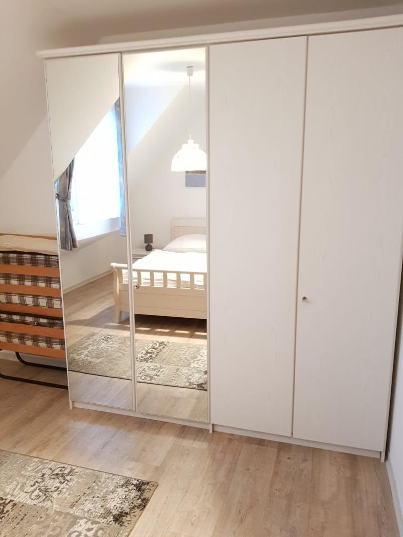 Bedroom with mirrored wardrobe, bed, and wooden floor.