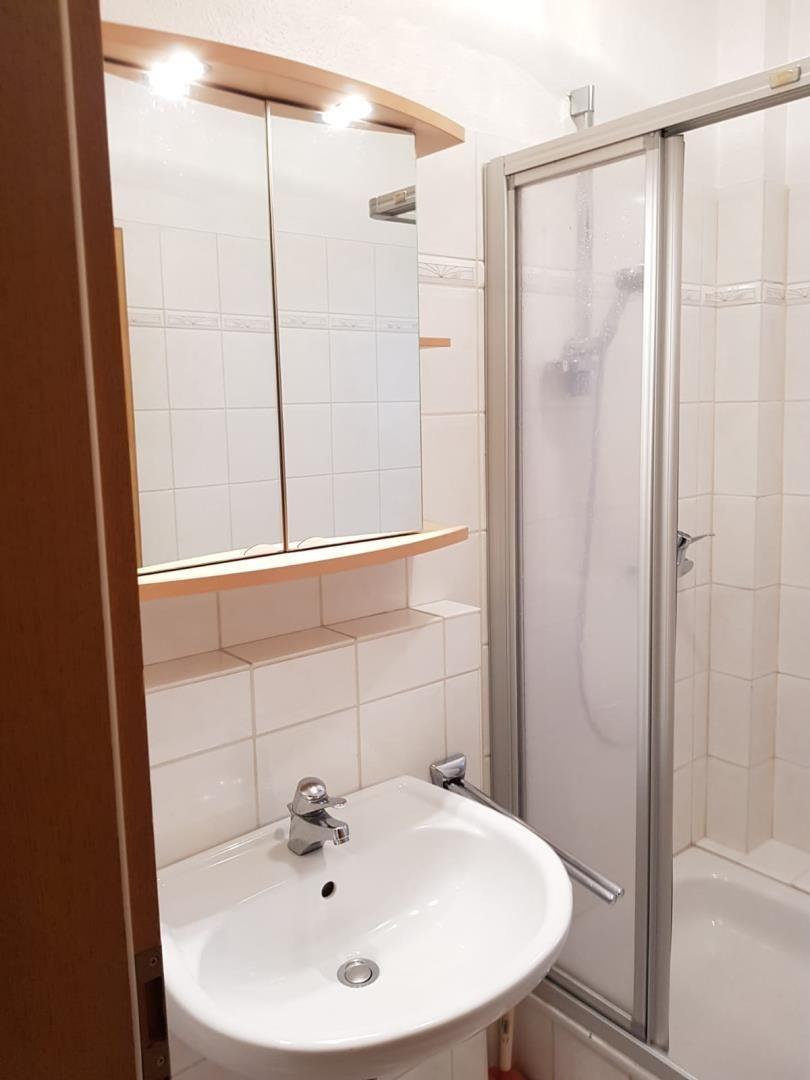 Bathroom with shower, sink, and mirror cabinet.