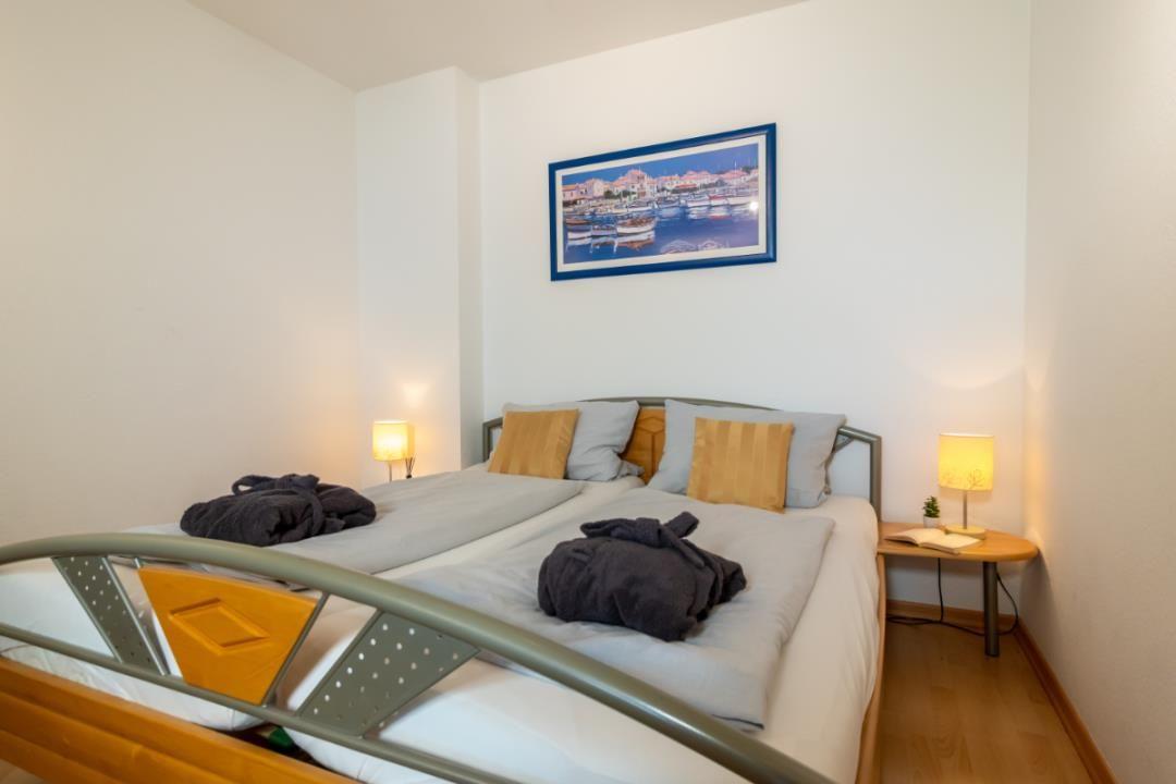 Schlafzimmer mit Doppelbett, zwei Nachttischen und Wandbild.