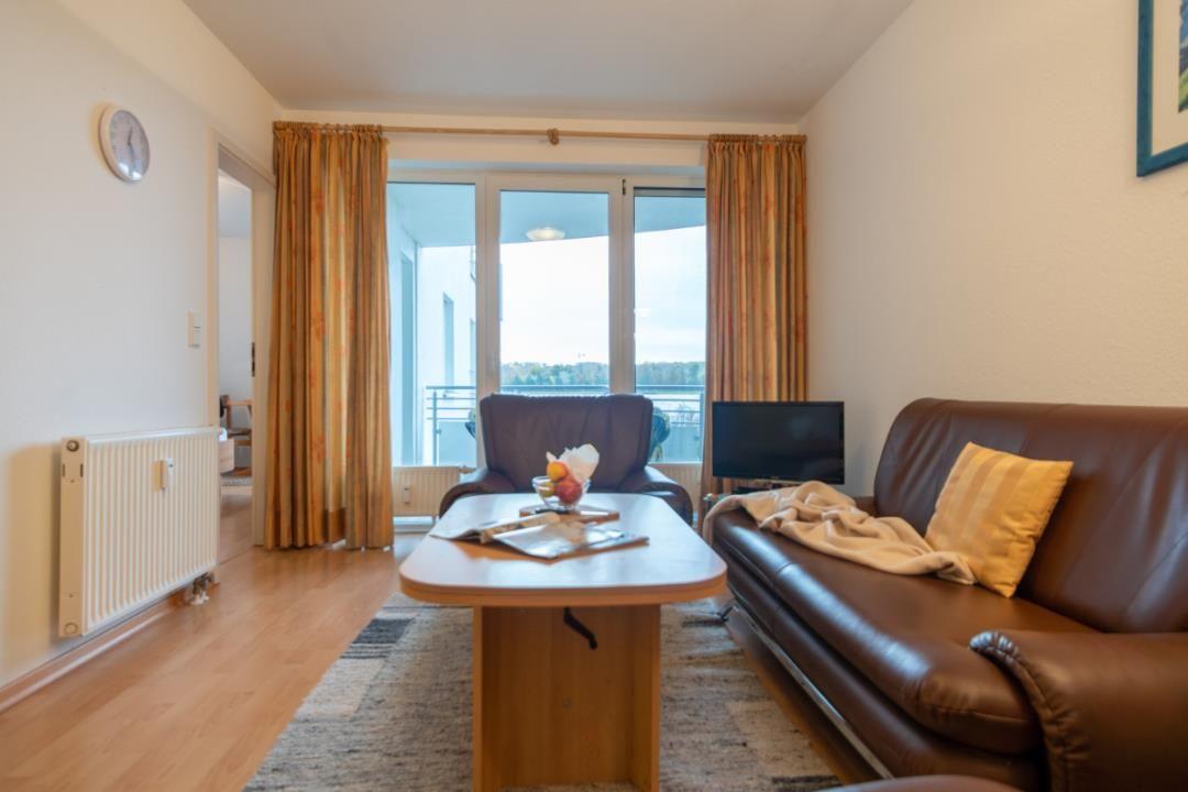 Wohnzimmer mit Sofa, Tisch und Balkonansicht.