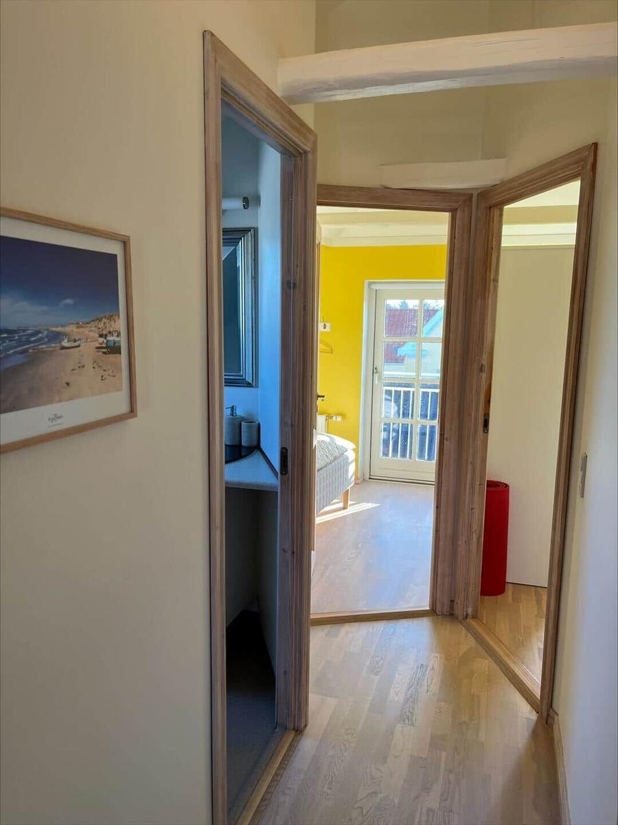 Hallway with wooden floor, door to bedroom and bathroom, wall picture with beach motif