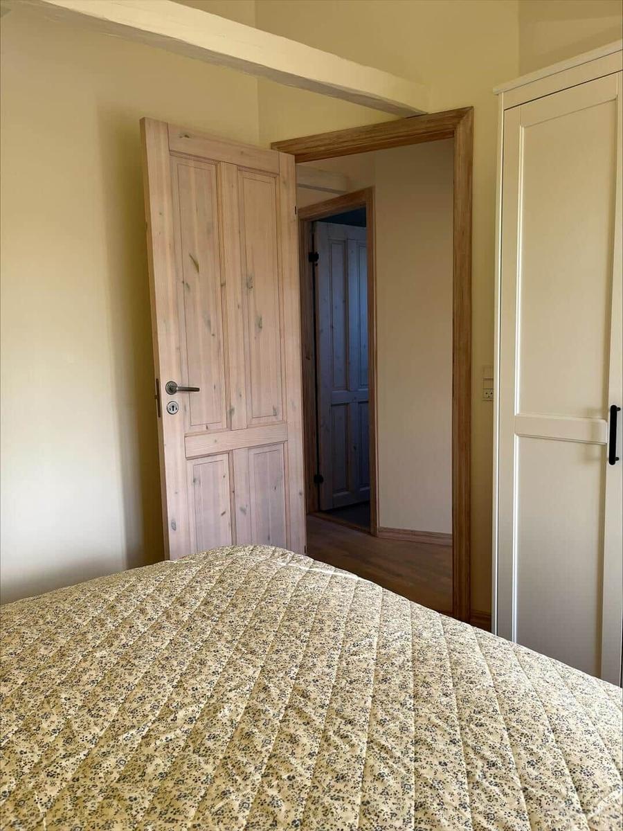 Bedroom with bed, wooden door, and wardrobe. Passage to another room.