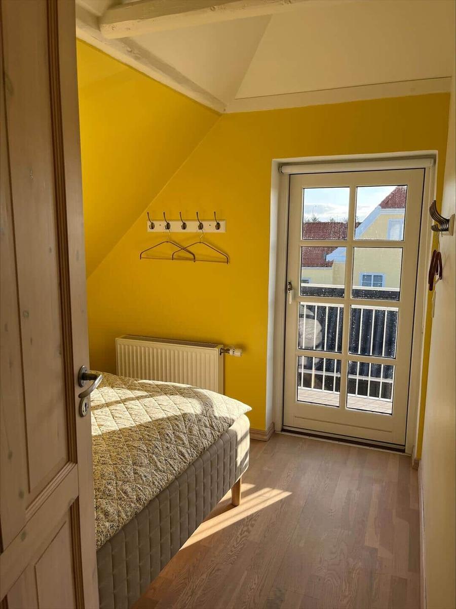 Bedroom with yellow walls, bed, and door to balcony.