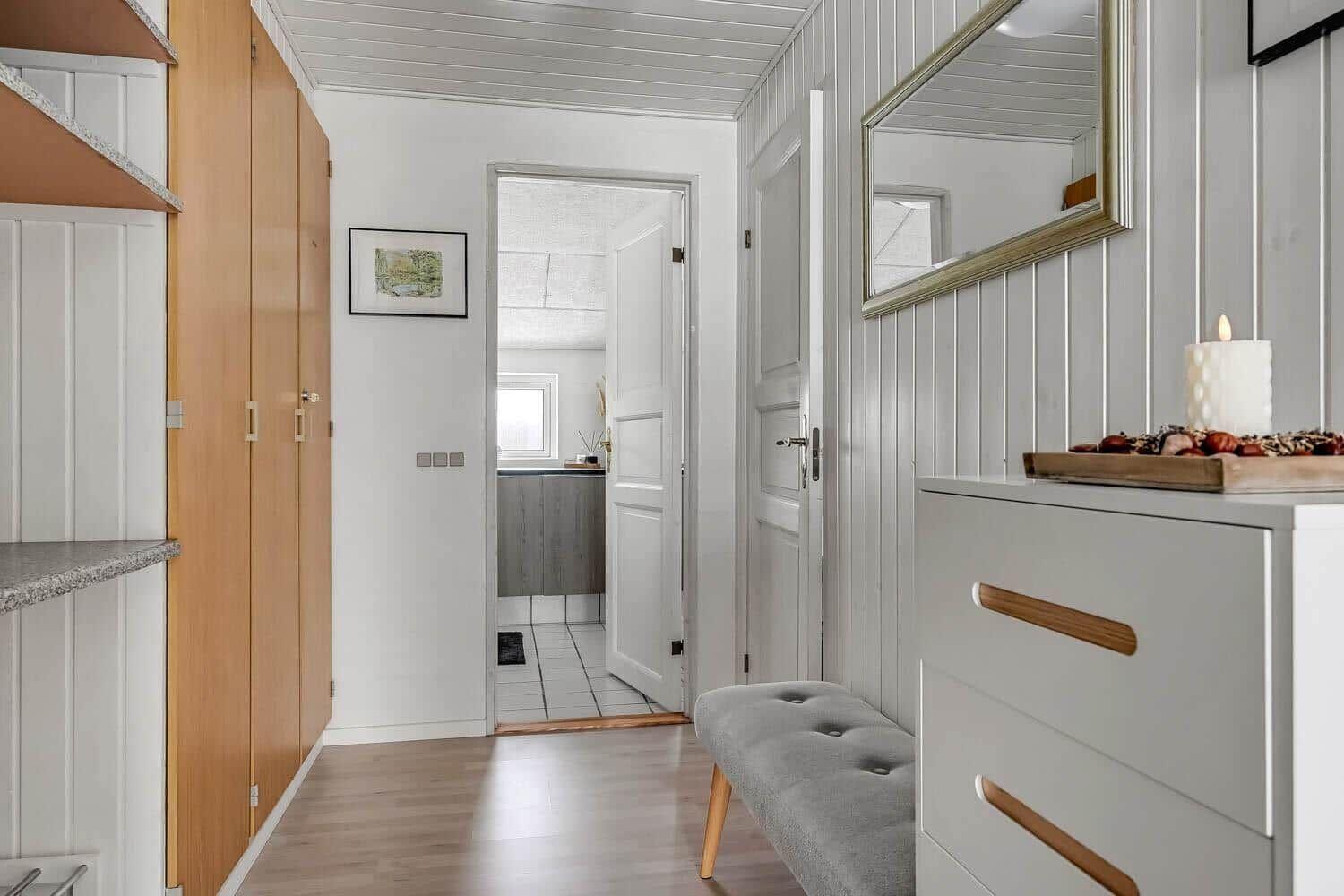 Hallway with closet, mirror, and bench. Passage to kitchen and bathroom.
