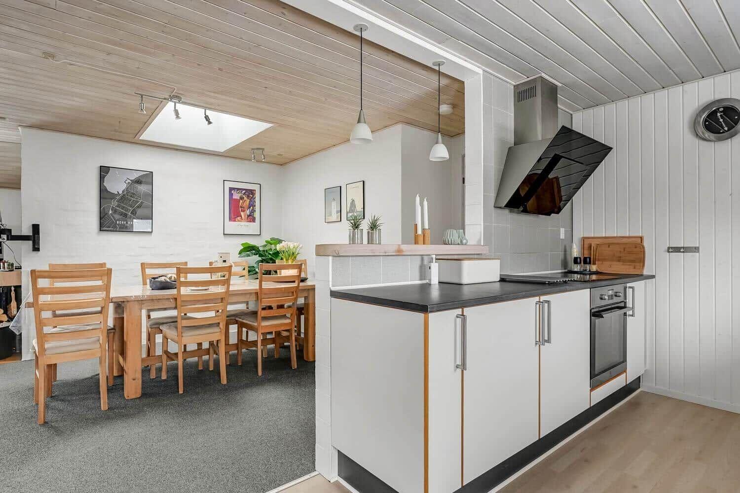 Kitchen with dining area, wooden table, white cabinets, and wooden ceiling.