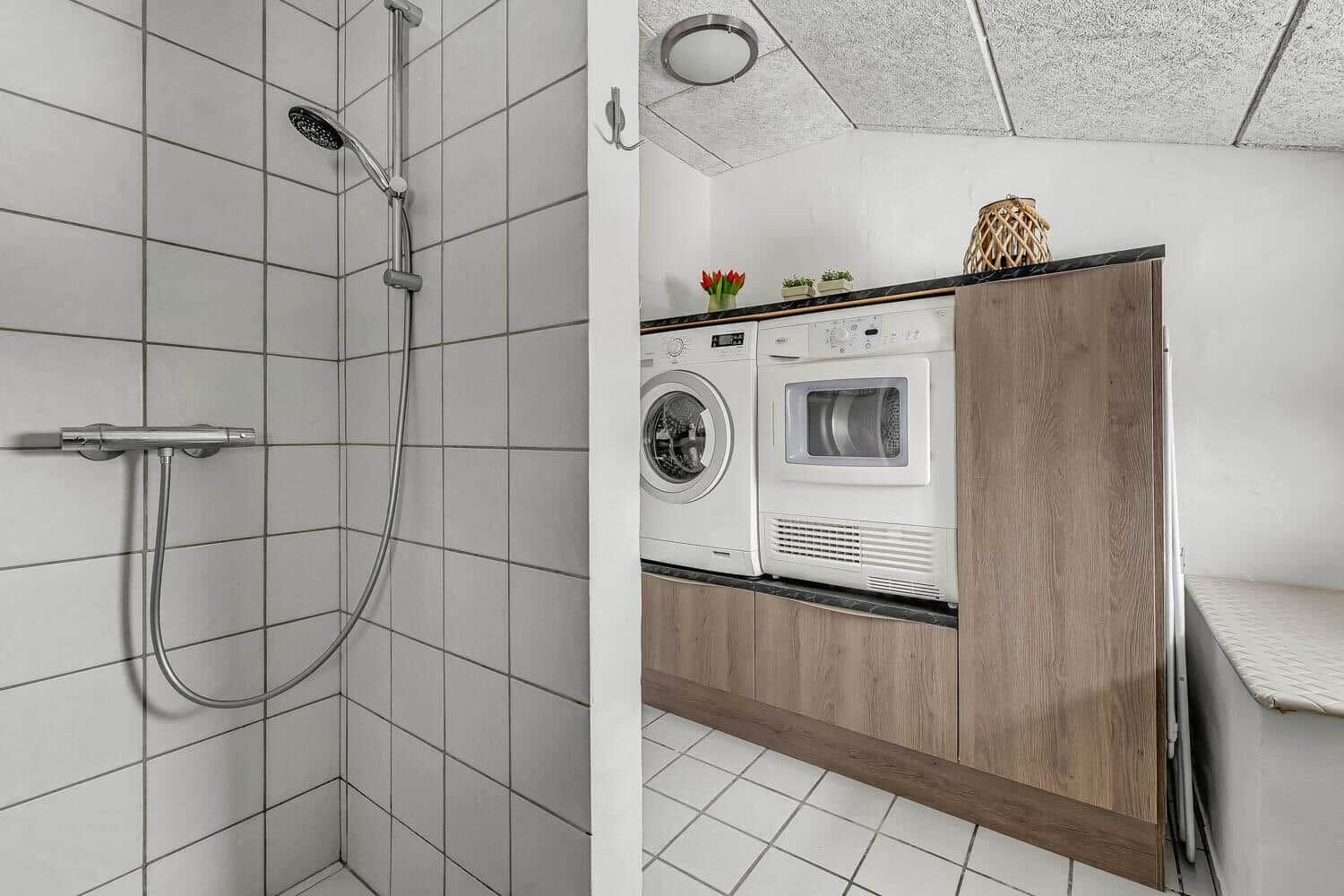 Shower with showerhead and washing machine next to dryer.