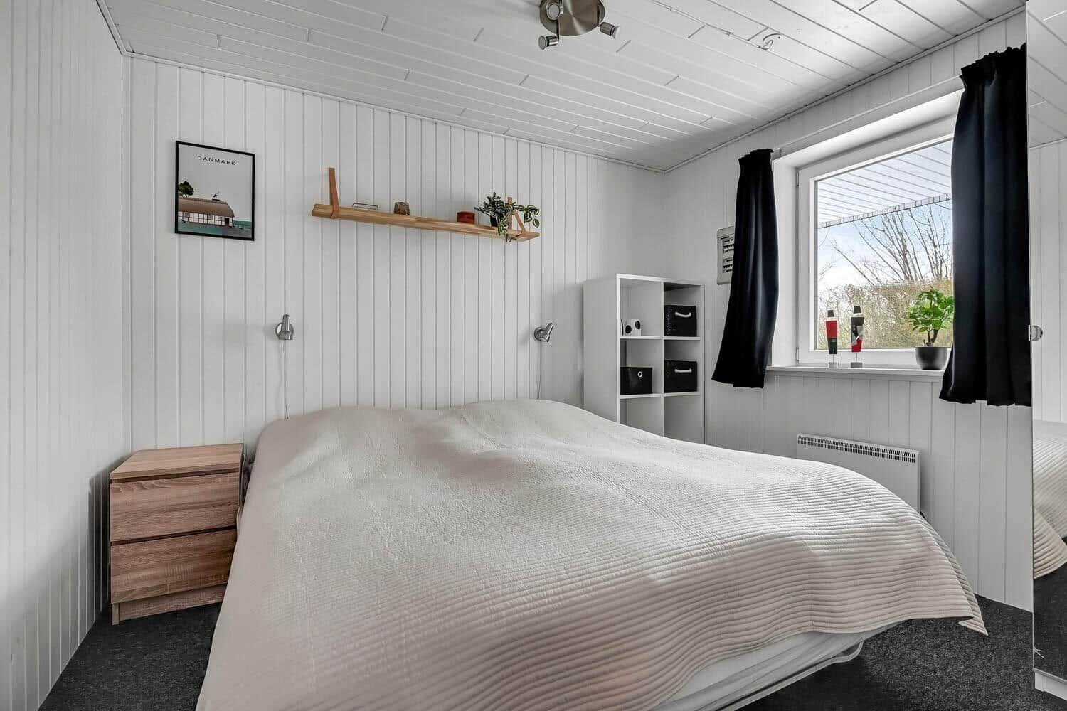Bedroom with bed, nightstand, shelving, and window with view outside.