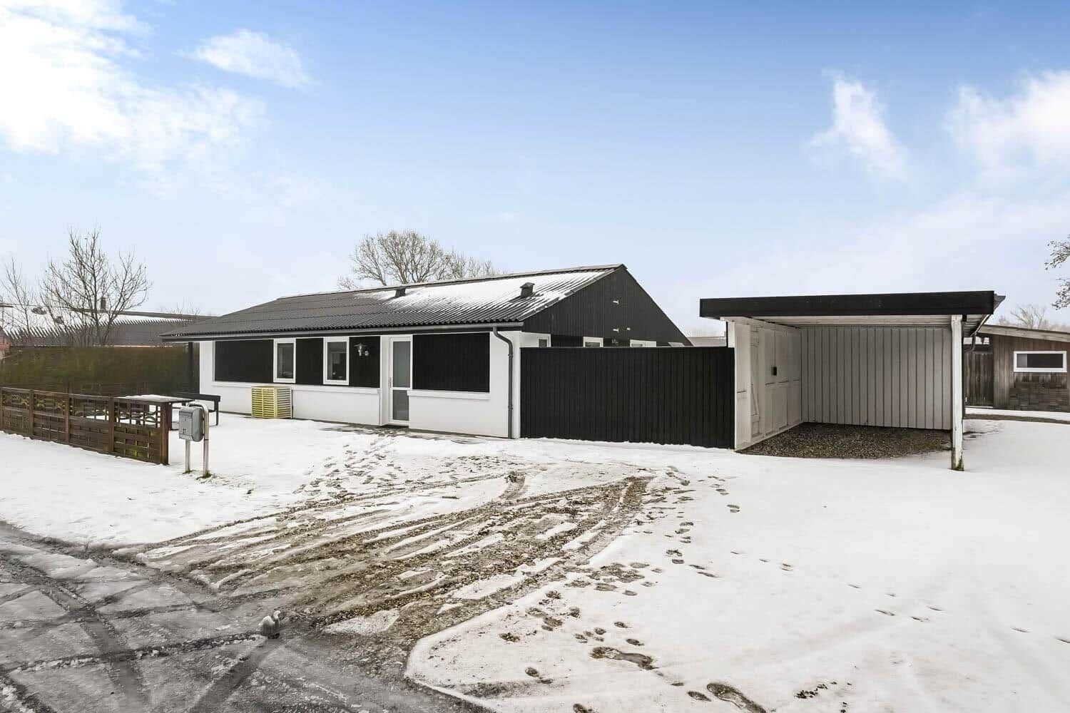 A modern house with a snow-covered yard and garage.