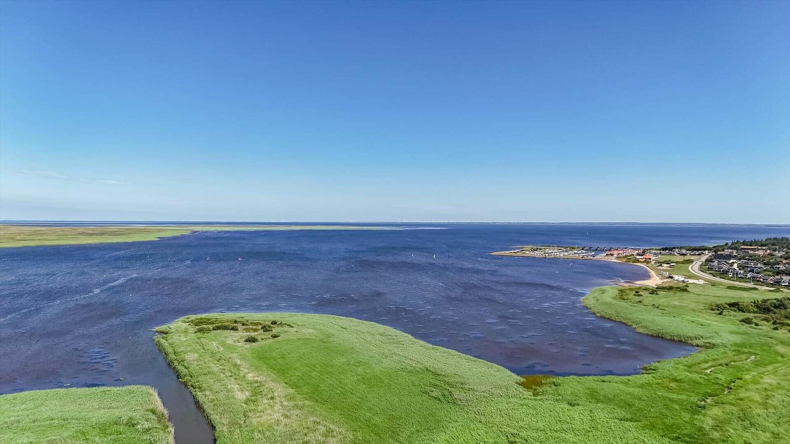 Wide view of coastal landscape with water, green areas, and holiday homes.
