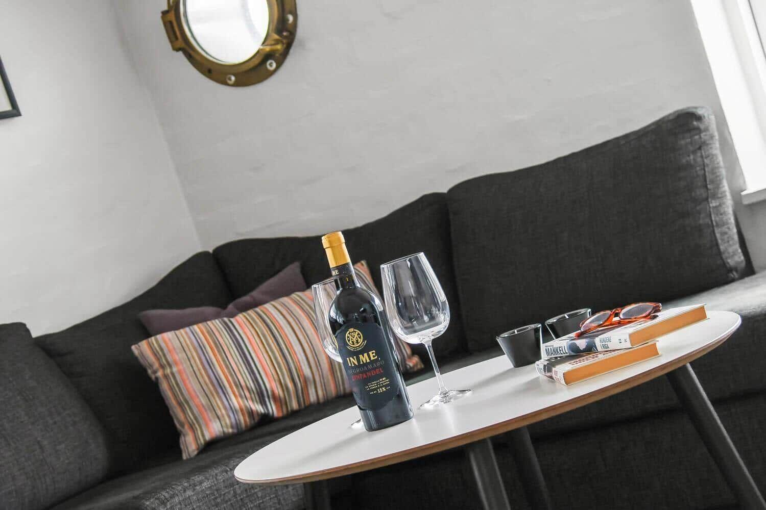 Living room with gray sofa, round table, and wine bottle.