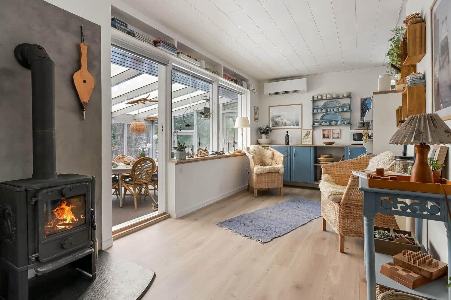Wohnraum mit Kamin, Sitzgelegenheiten und Blick in die Küche.