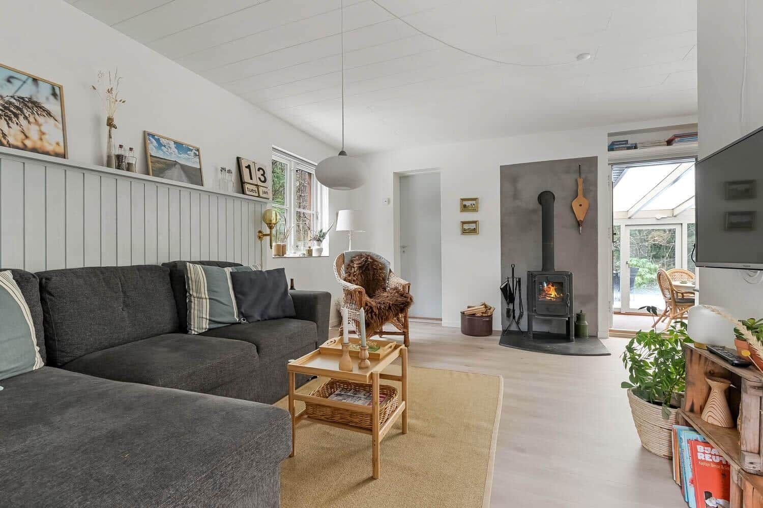 Wohnzimmer mit Sofa, Kamin und Fenster zur Terrasse.