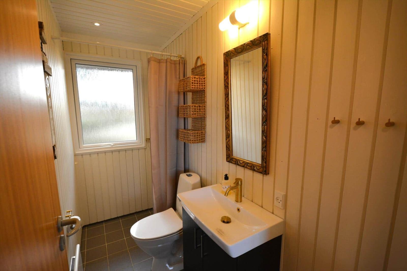 Badezimmer mit Toilette, Waschbecken und Dusche mit Vorhang.