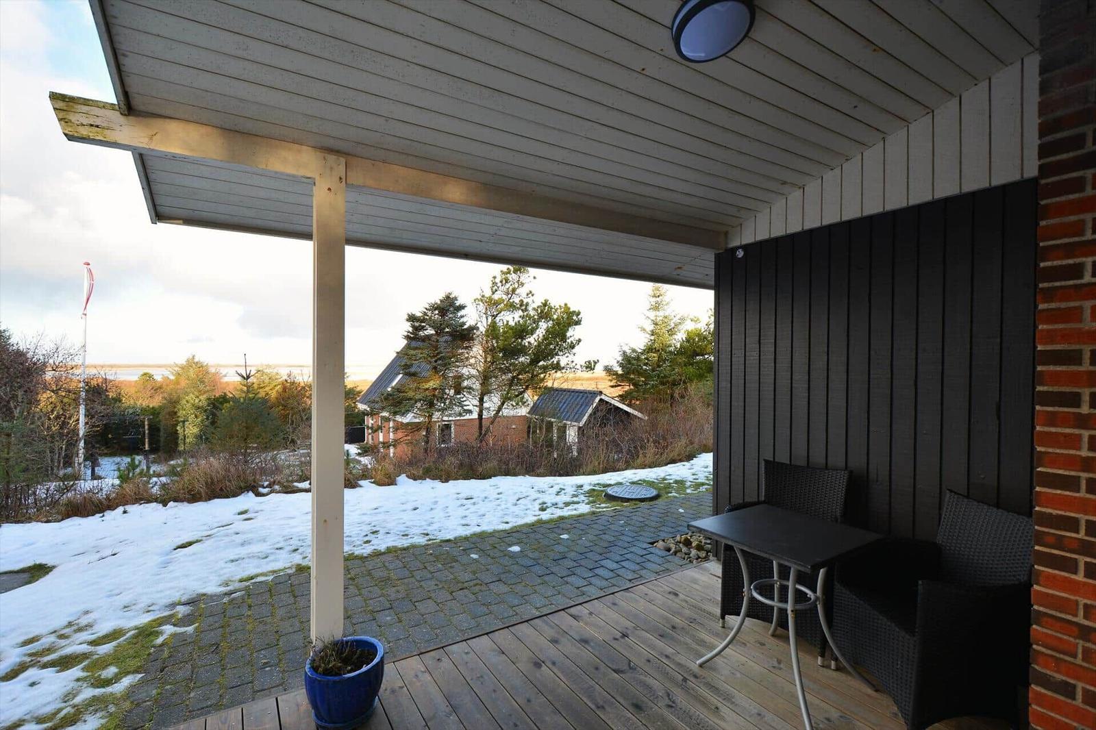 Terrasse mit Tisch und Stühlen, Blick auf verschneite Landschaft und Häuser.