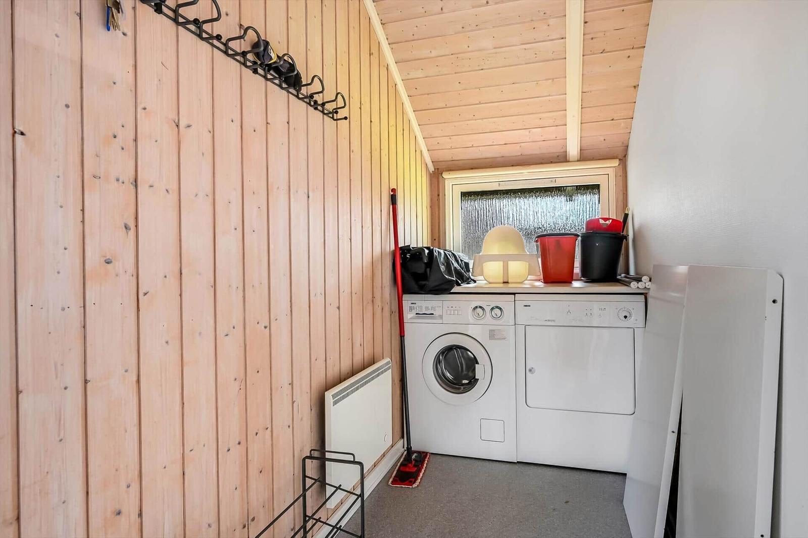 Wäschetrockner und Waschmaschine in einem Raum mit Holzwand und Fenster.